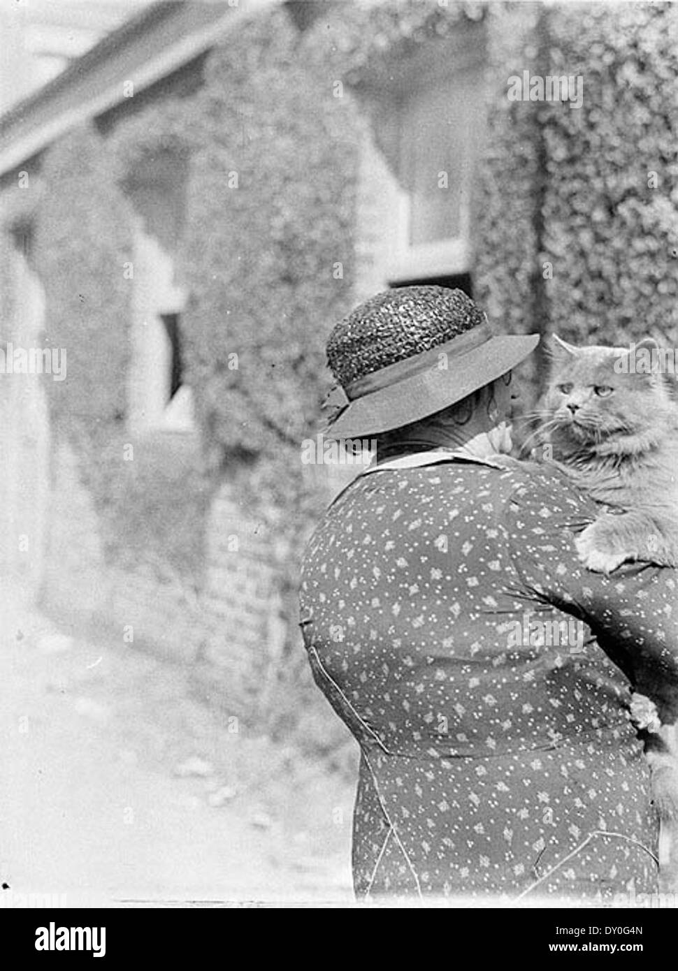 This photograph from the 1935 Royal Easter Show, captured by Sam Hood, features a woman with a cat at the Sydney Showground. The image highlights the variety of exhibits at the event, including animals, and the fashionable attire of attendees. Stock Photo