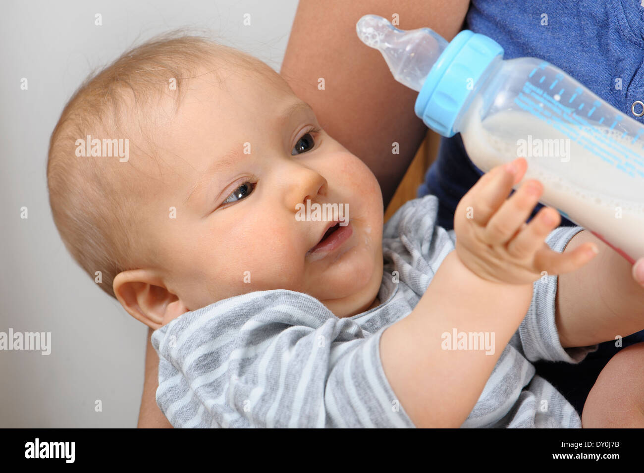 Baby bottle feeding milk in his mother's arms Stock Photo