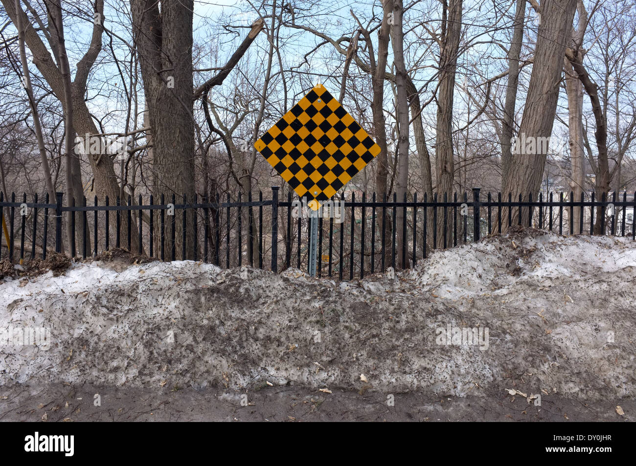 A black and yellow checkered warning sign at the end of a road Stock
