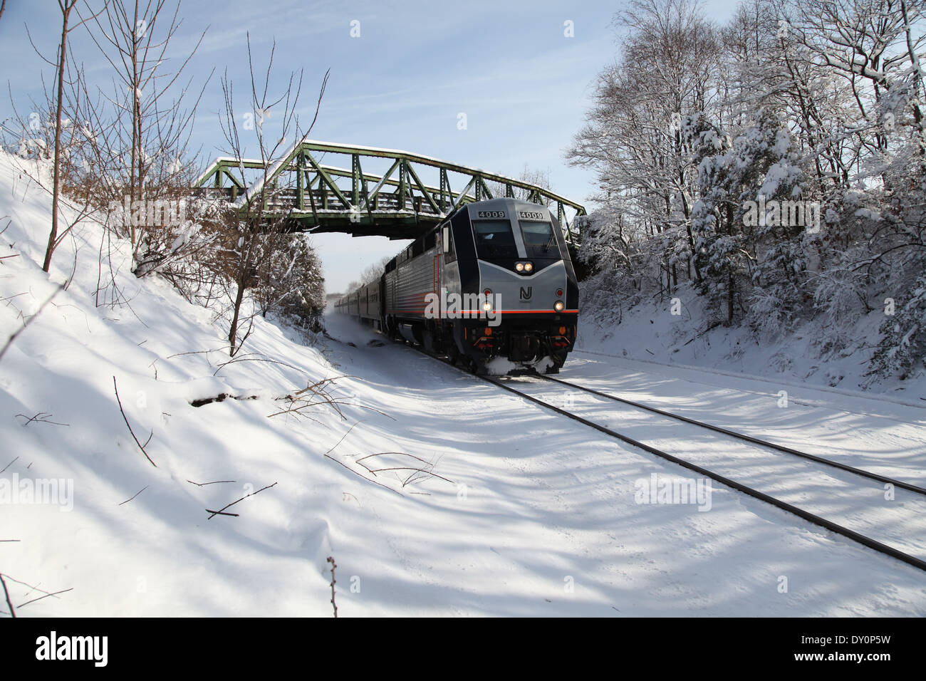 New Jersey Transit Train glides along snow-covered tracks near Whitehouse Station in Readington Township, New Jersey Stock Photo