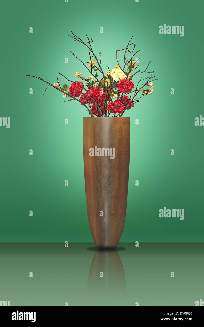 Red and yellow flowers in a large metal vase on a green background