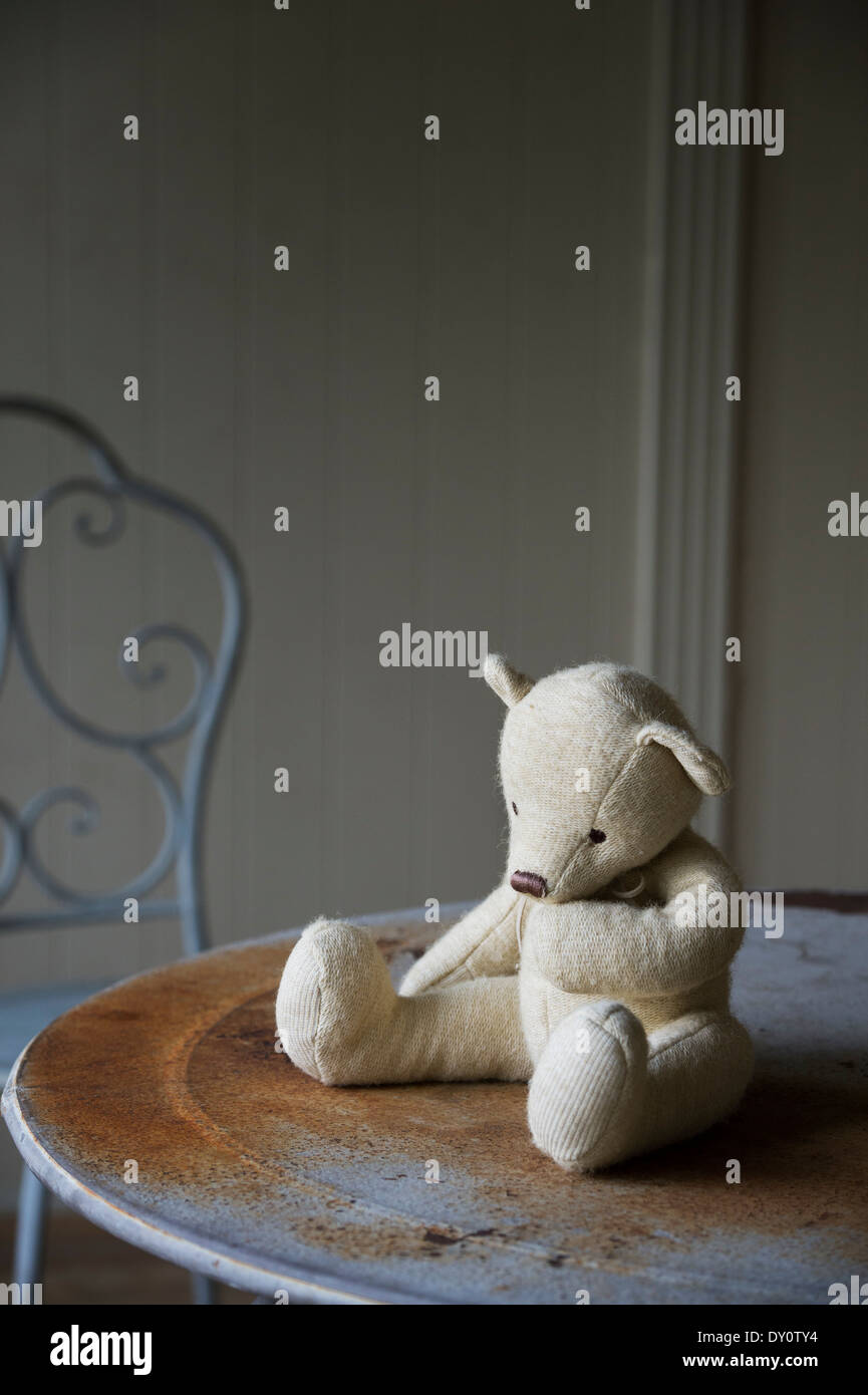 Thoughtful Teddy bear sat on a seat in a garden summer house Stock Photo