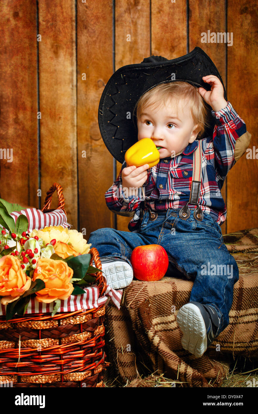 Little Cowboy on a farm in a hat and jeans after harvest Stock Photo