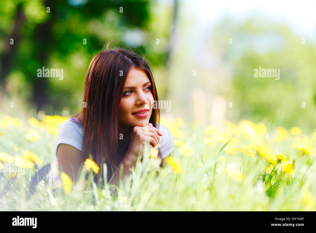 Beautiful young woman lying on grass with flowers Stock Photo - Alamy