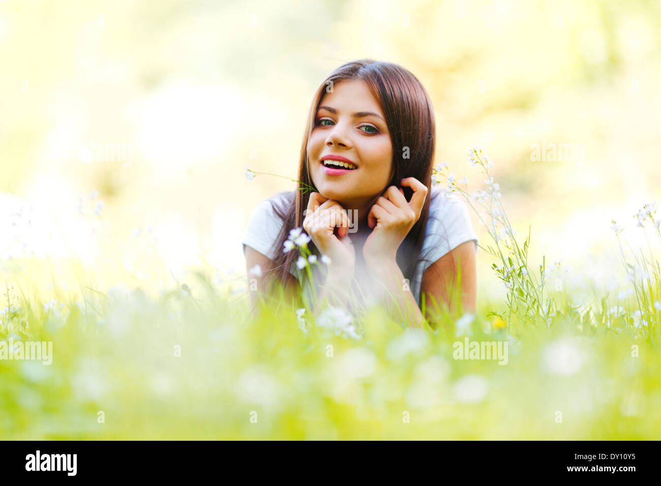 Beautiful young woman lying on grass with flowers Stock Photo - Alamy