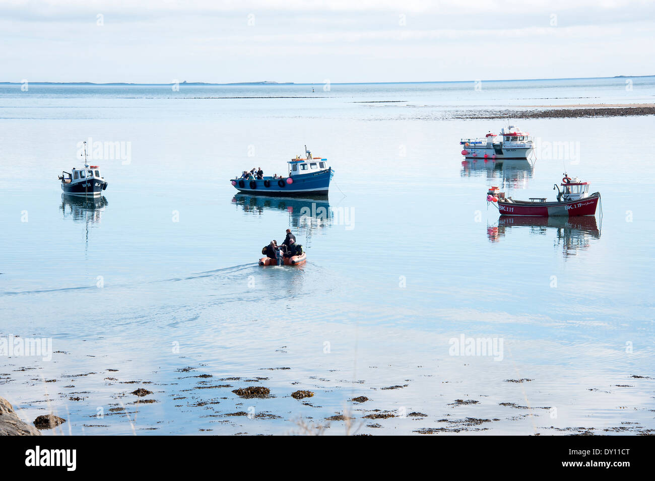 Fishing Boats Moored near Holy Island Harbour in Flat Calm Water with a Dinghy Lidisfarne Northumberland England United Kingdom Stock Photo
