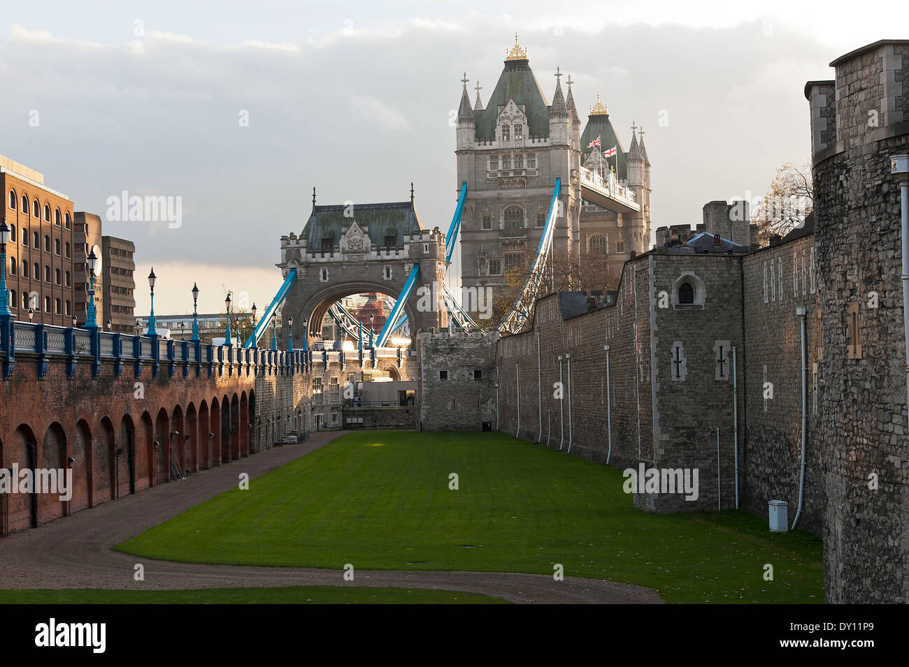 Thick Stone Walls of The Tower of London with Lawned Area and Tower Bridge in City of Westminster London England United Kingdom Stock Photo
