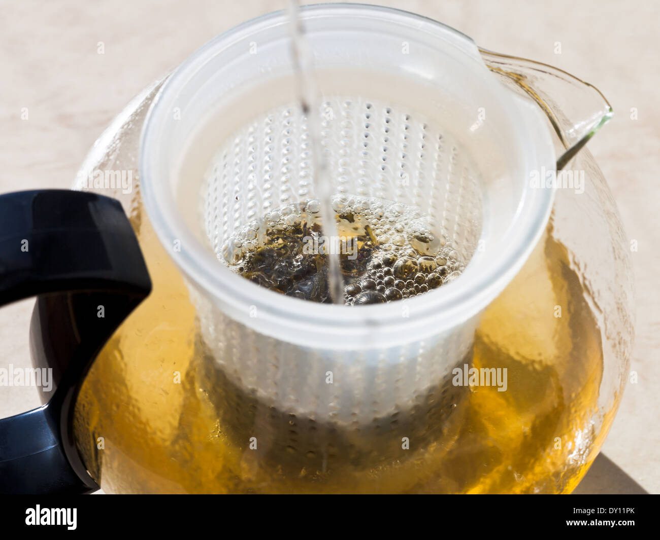 making green tee in glass teapot with boiling water Stock Photo
