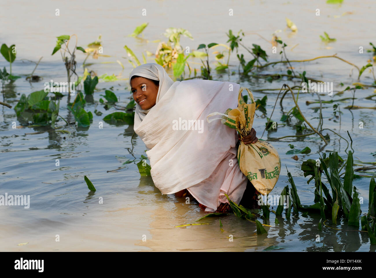 BANGLADESH District Bagerhat , cyclone Sidr and high tide destroy villages in South khali, river Balaswar, distribution of relief goods to affected people in villages, girl wading in the water with bags with relief goods Stock Photo