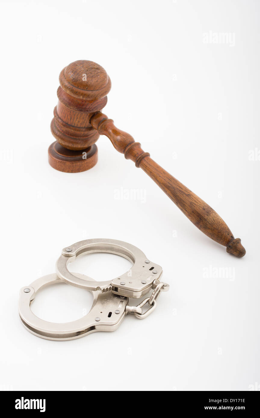 Wooden judges gavel ( ceremonial mallet ) with sounding block from courtroom and standard police issue Smith & Wesson handcuffs Stock Photo