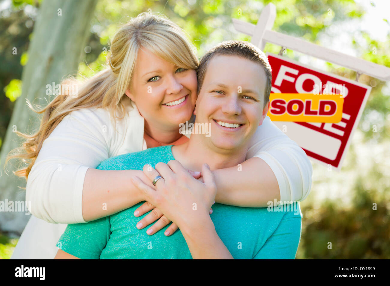 Happy Couple Hug In Front of Sold Real Estate Sign Stock Photo - Alamy