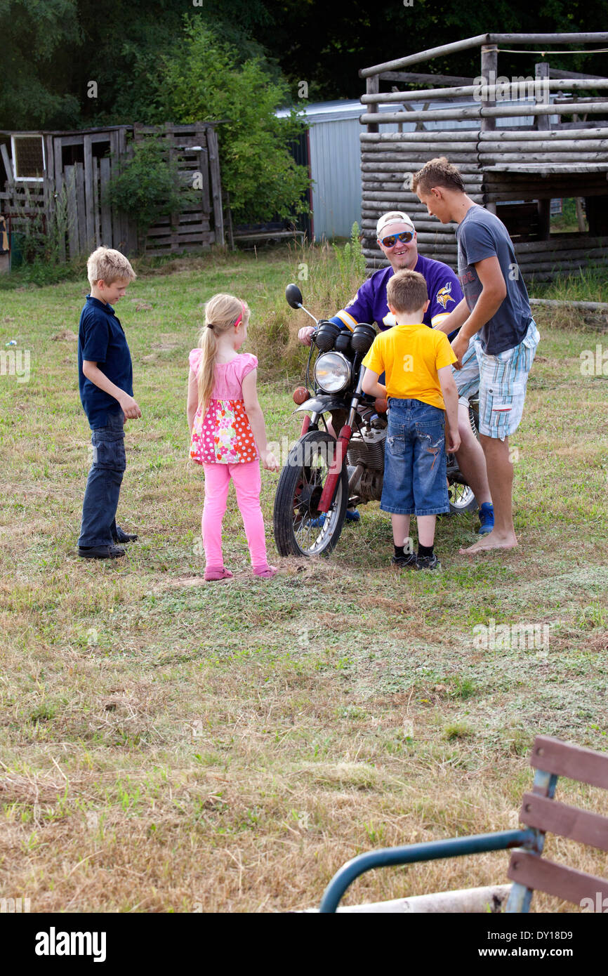 Dad showing off to his kids on teen visitors motorcycle. Zawady Central Poland Stock Photo