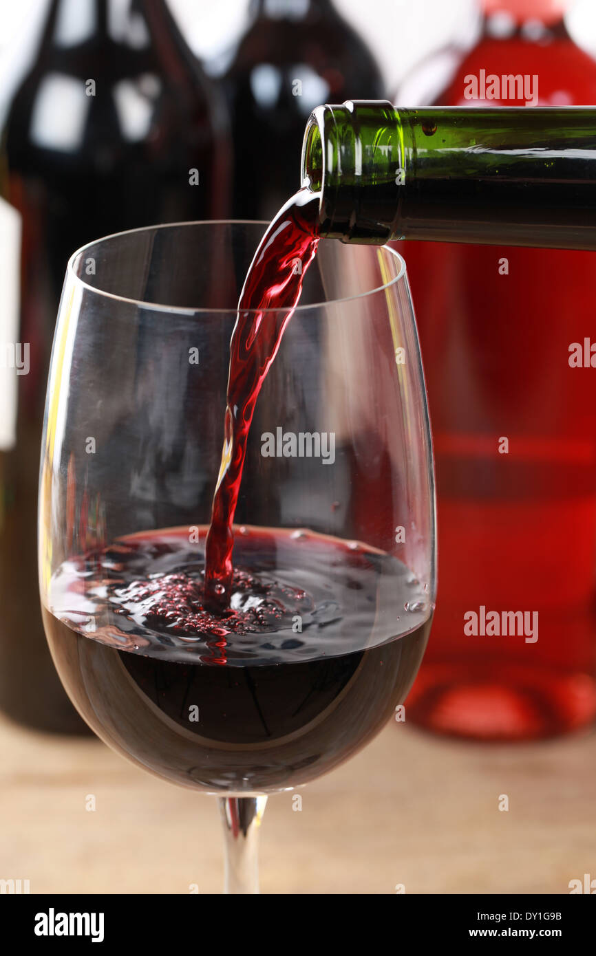 Red wine pouring from a bottle into a wine glass. Stock Photo