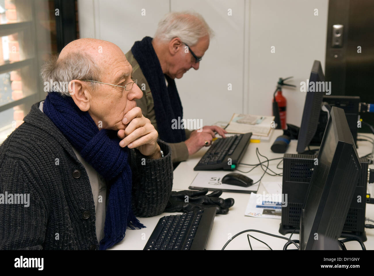 Elderly men using the computer at their local library, Alton, Hampshire, UK. Stock Photo