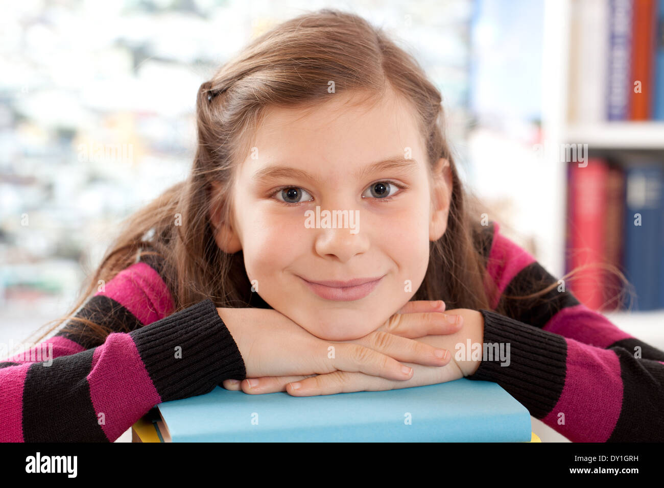 Little girl holding her head on a stack of books Stock Photo