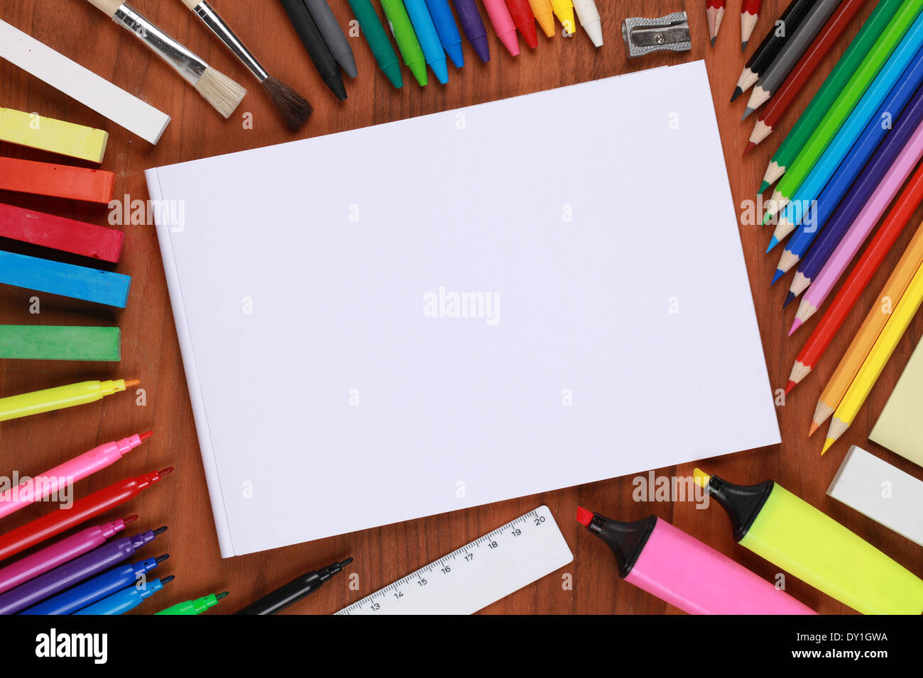 Empty notebook with copyspace, surrounded by crayons, pencils and other school equipment Stock Photo