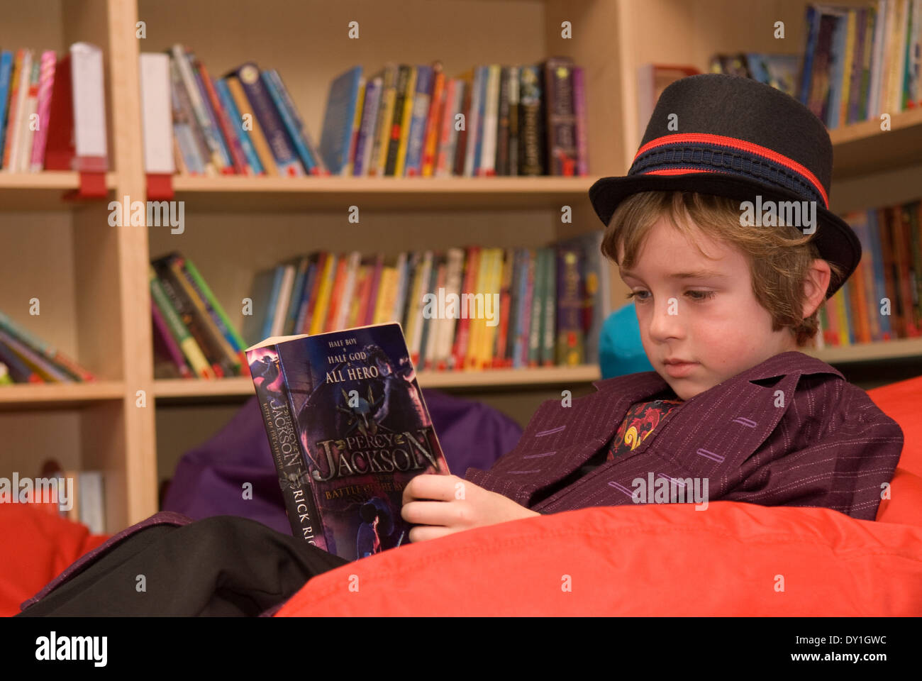 7 year old pupil reading in school library in costume for World Book Day, Haslemere, Surrey, UK. Stock Photo