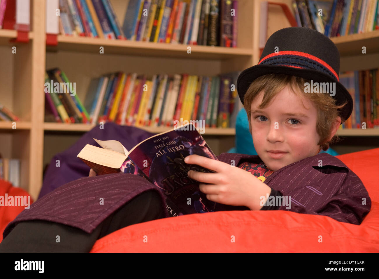 7 year old pupil reading in school library in costume for World Book Day 2014, Haslemere, Surrey, UK. Stock Photo