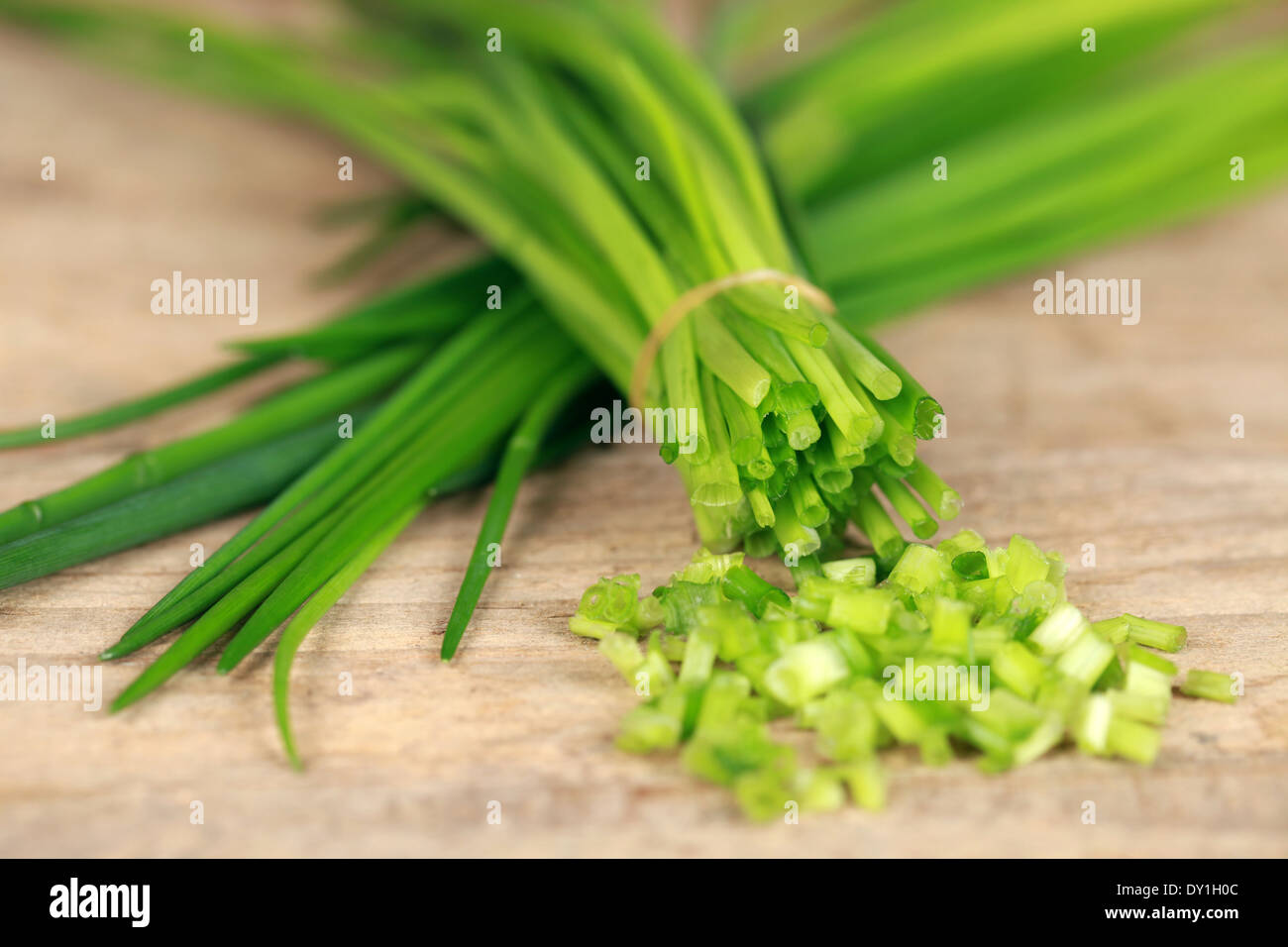Chopped chives on wooden board, shallow depth of field Stock Photo