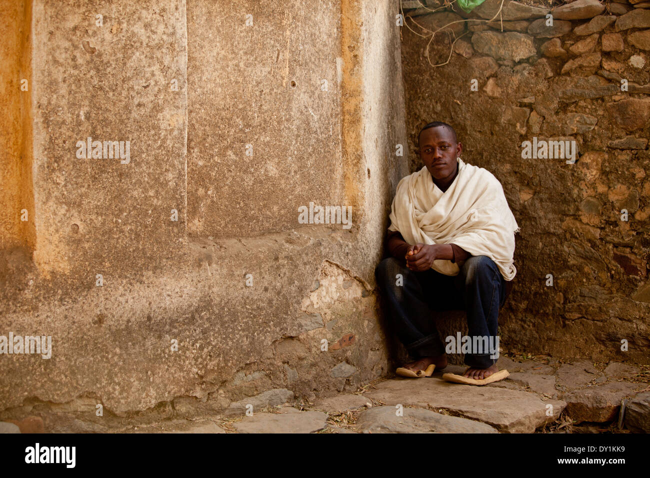 Ethiopian Man sat by stone wall in shawl Stock Photo