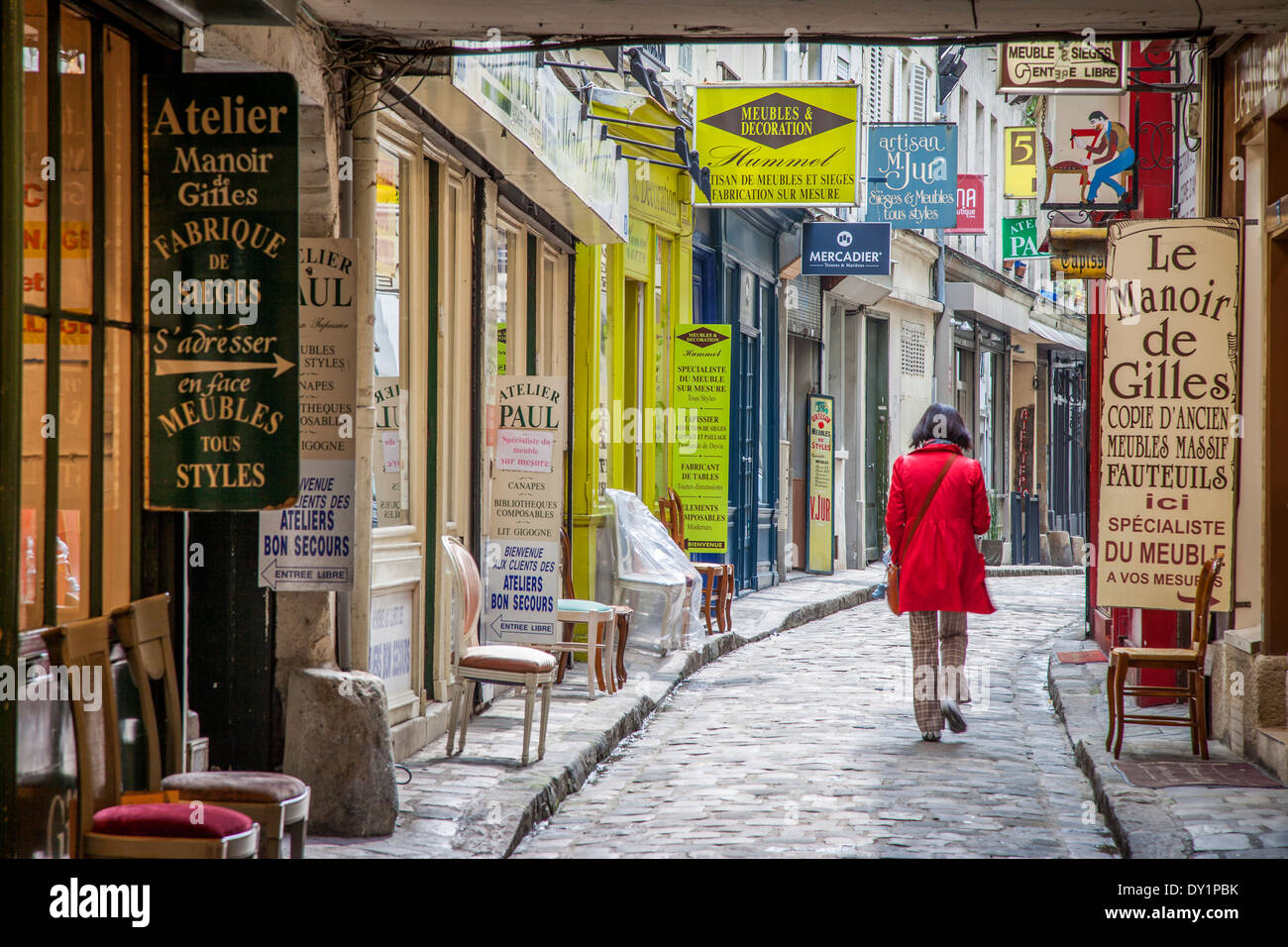 Woman in red coat walking down Passage du Chantier, near Faubourg Saint Antoine, Paris, France Stock Photo