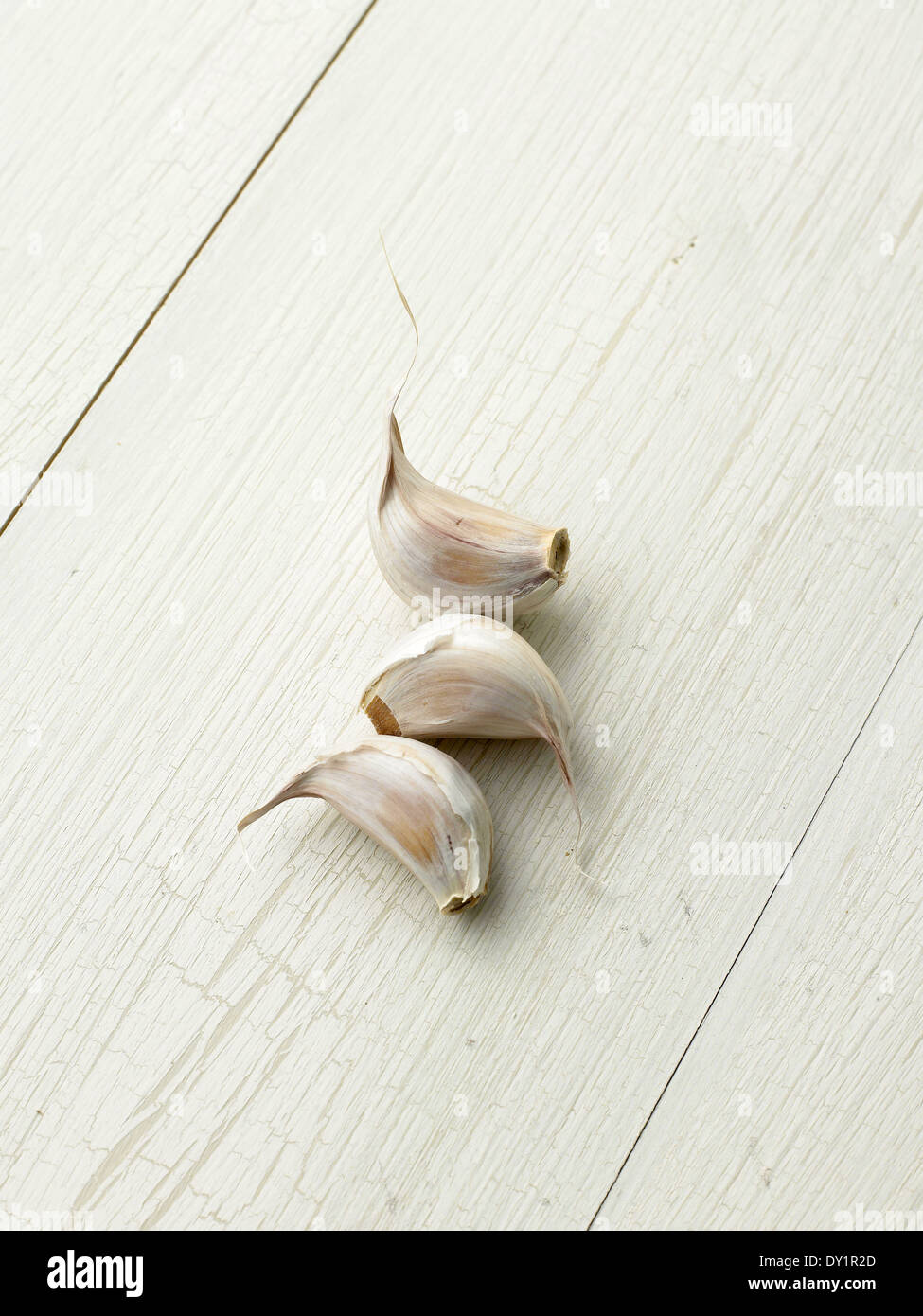 Three Garlic Cloves on light wood background Stock Photo