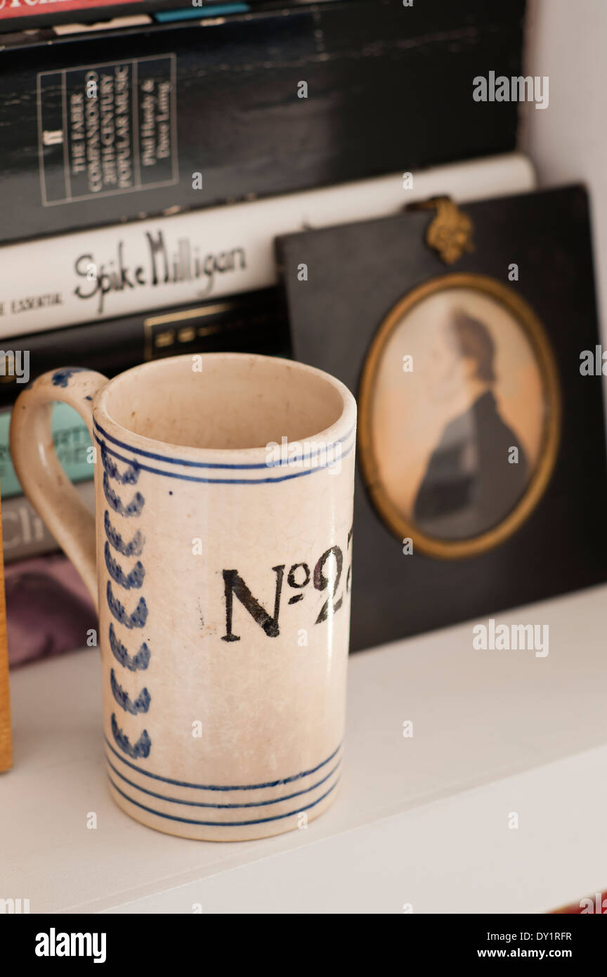 Detail of an old numbered mug on a bookshelf Stock Photo