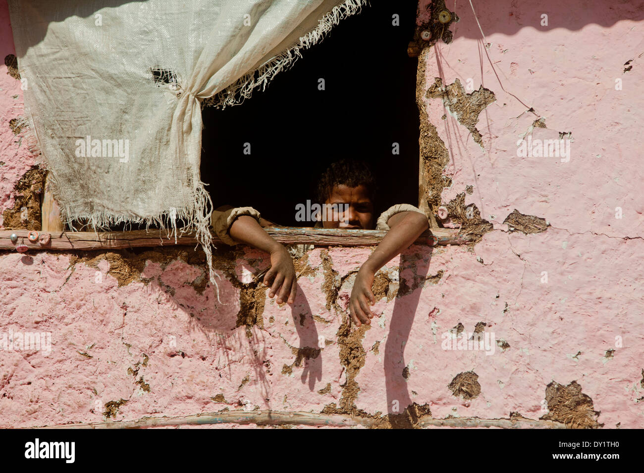 Ethiopian boy hanging arms out of window mud hut Stock Photo