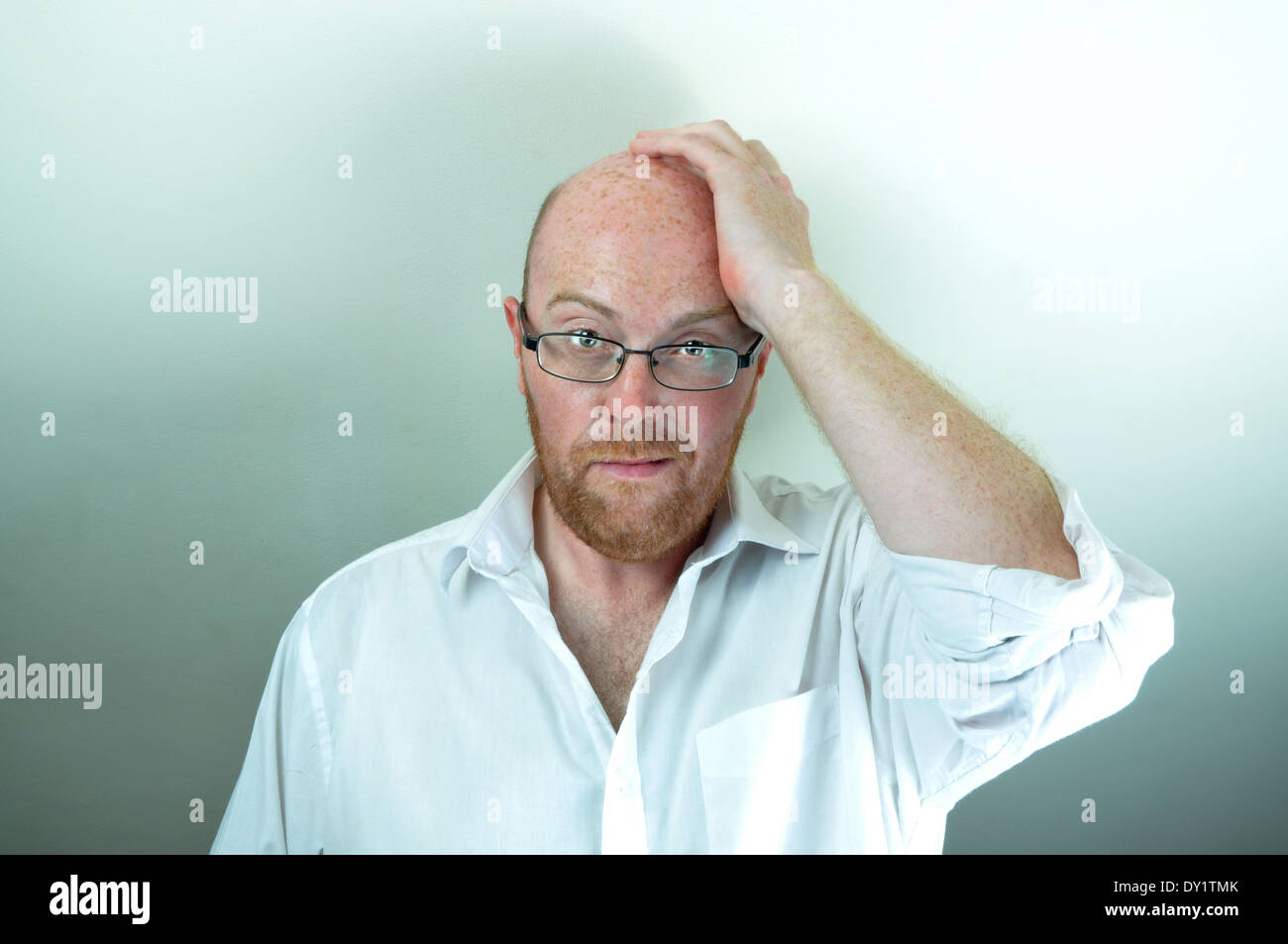 Bald man rubbing his head Stock Photo