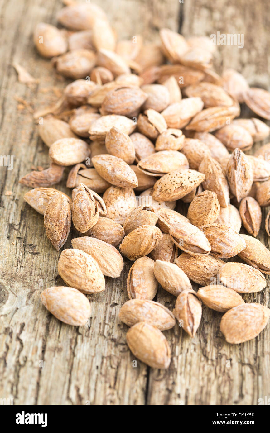 Roasted salted almonds in their shells, scattered over rustic wooden board Stock Photo Alamy