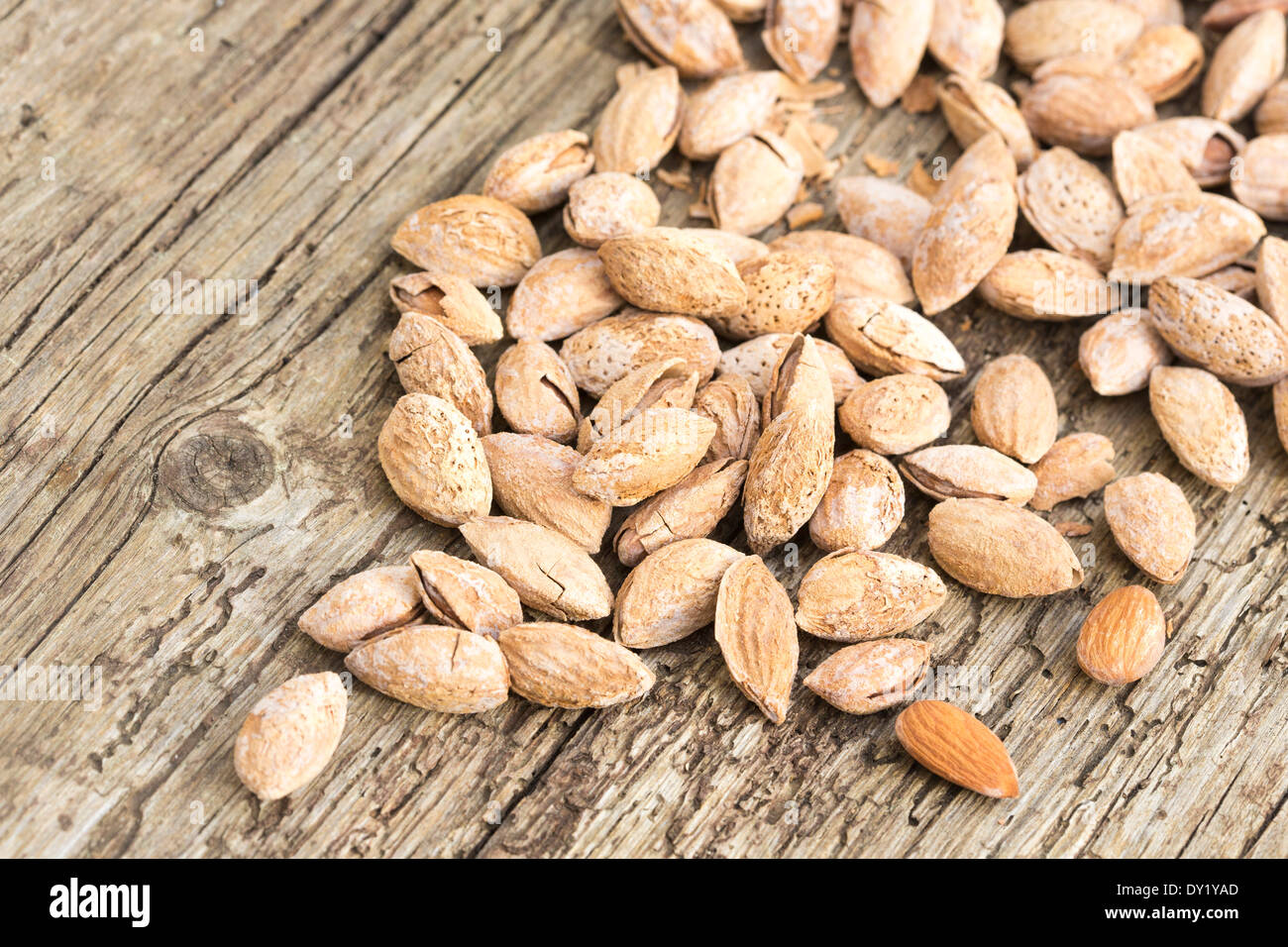 roasted salted almonds in their shells, scattered over rustic wooden board Stock Photo Alamy