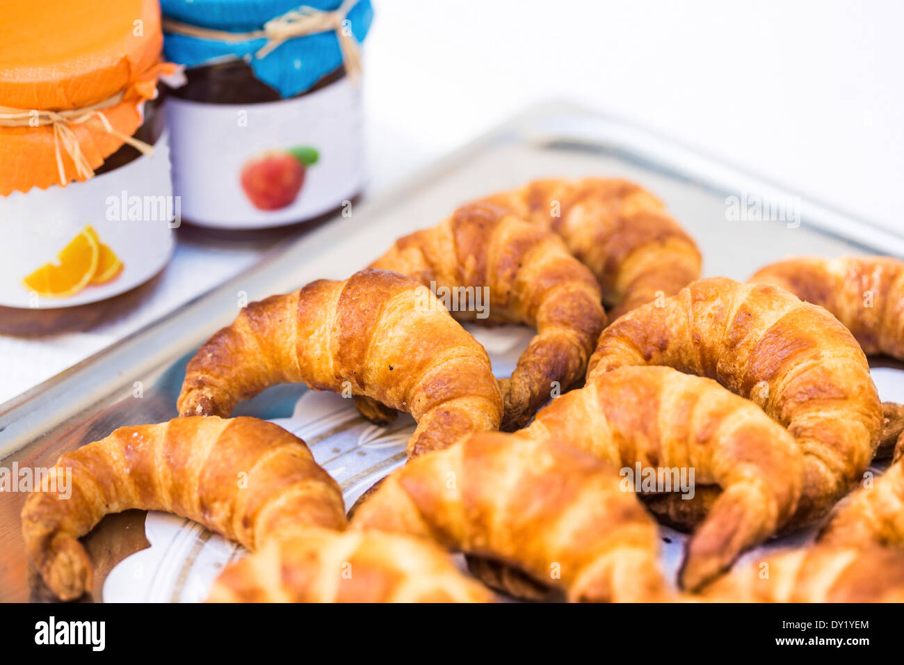 Tray of mini croissants on metal tray with assorted jam preserves in background, Stock Photo