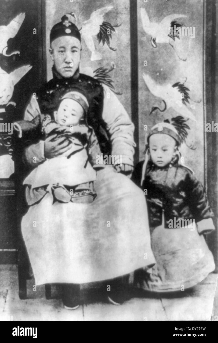 Three year old Emperor of China,  Pu Yi, throne name Hsuantung, on the right. On the left is his father, Prince Chun, the Regent, holding a younger brother. 1909 Stock Photo