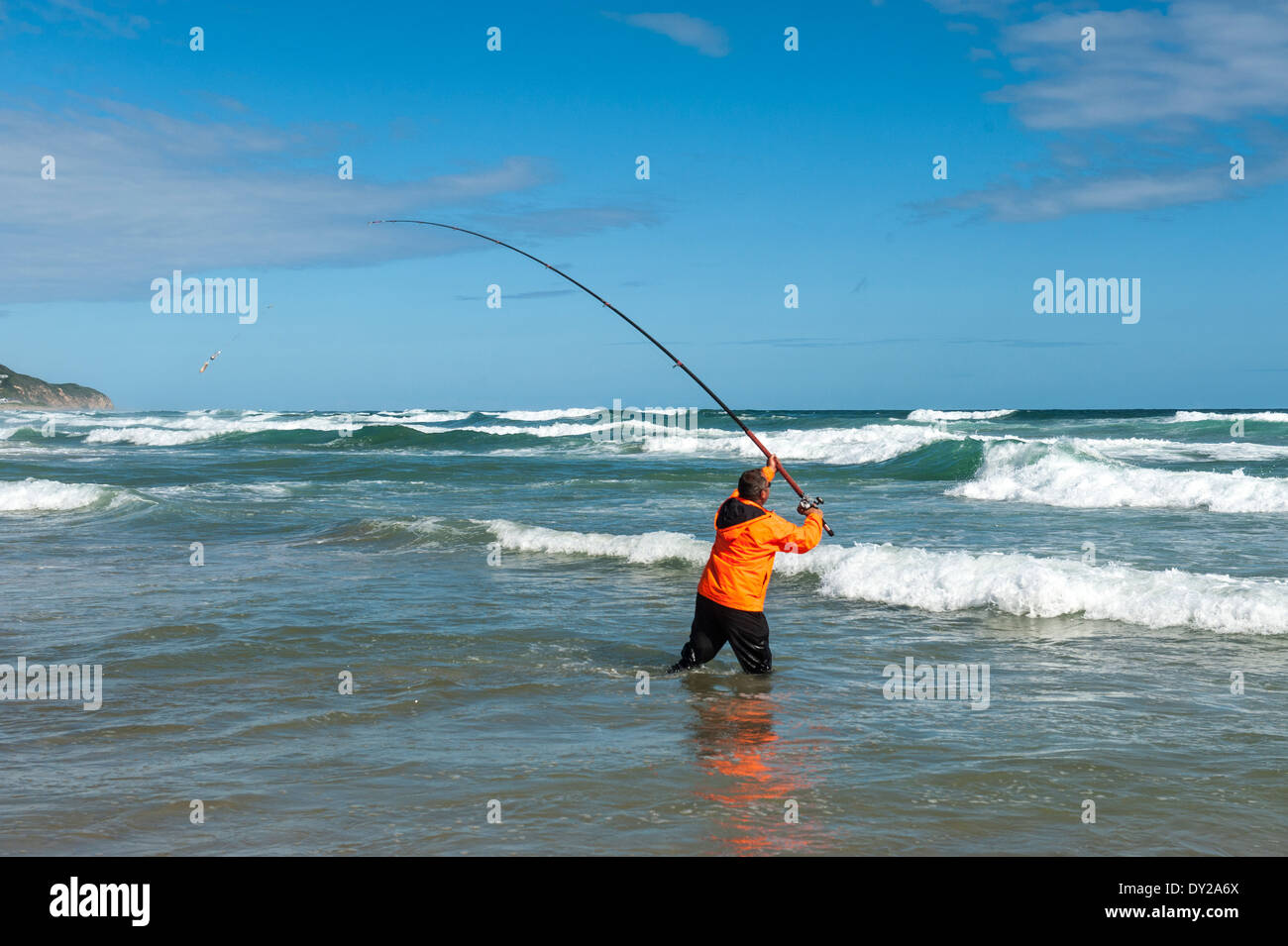 Surfcasting fisherman standing in the surf at Morgan Bay, Eastern Cape, South Africa Stock Photo