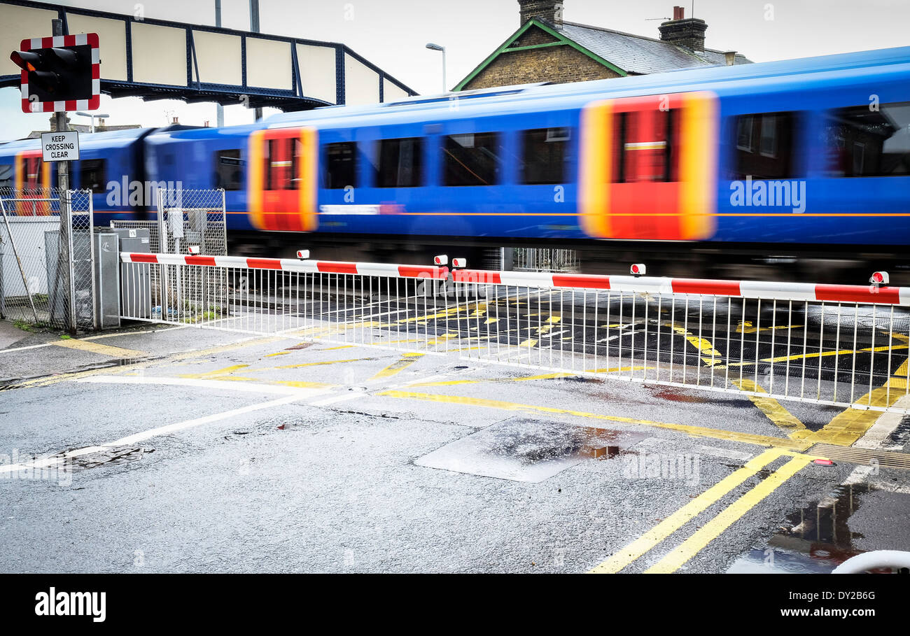 A train speeding across a railway level crossing. Stock Photo