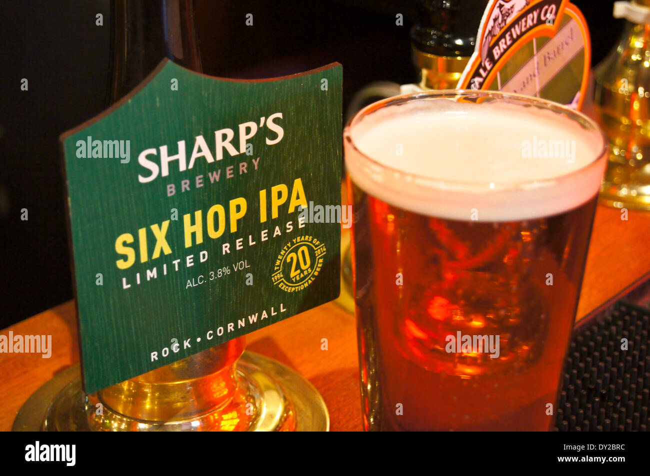 A pint of Sharp's Six Hop IPA real ale on a pub bar with its pump clip,  pub table drinks glasses Stock Photo