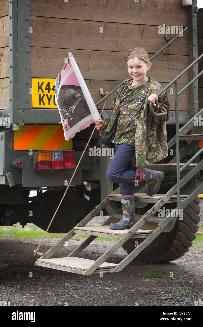 A young girl bush beater holding a home made flag while standing on the back of a beaters or guns truck on a shoot Stock Photo