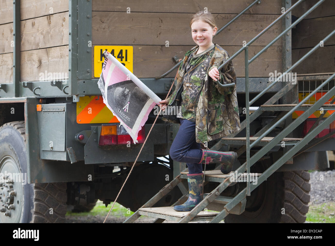 A young girl bush beater holding a home made flag while standing on the back of a beaters or