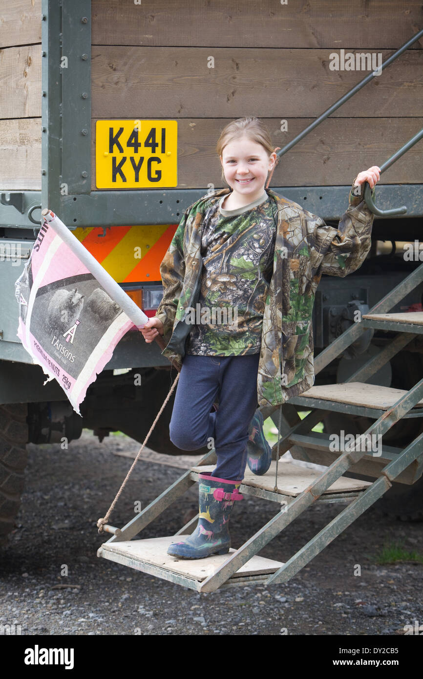 A young girl bush beater holding a home made flag while standing on the back of a beaters or