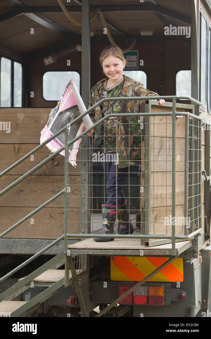 A young girl bush beater holding a home made flag while standing on the back of a beaters or