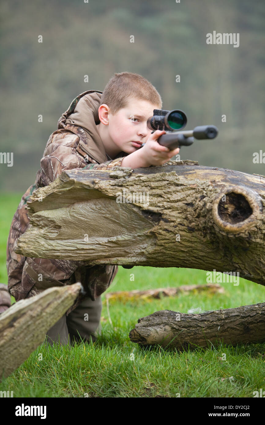 A young man with a rifle, shooting pests during the day in the countryside Stock Photo