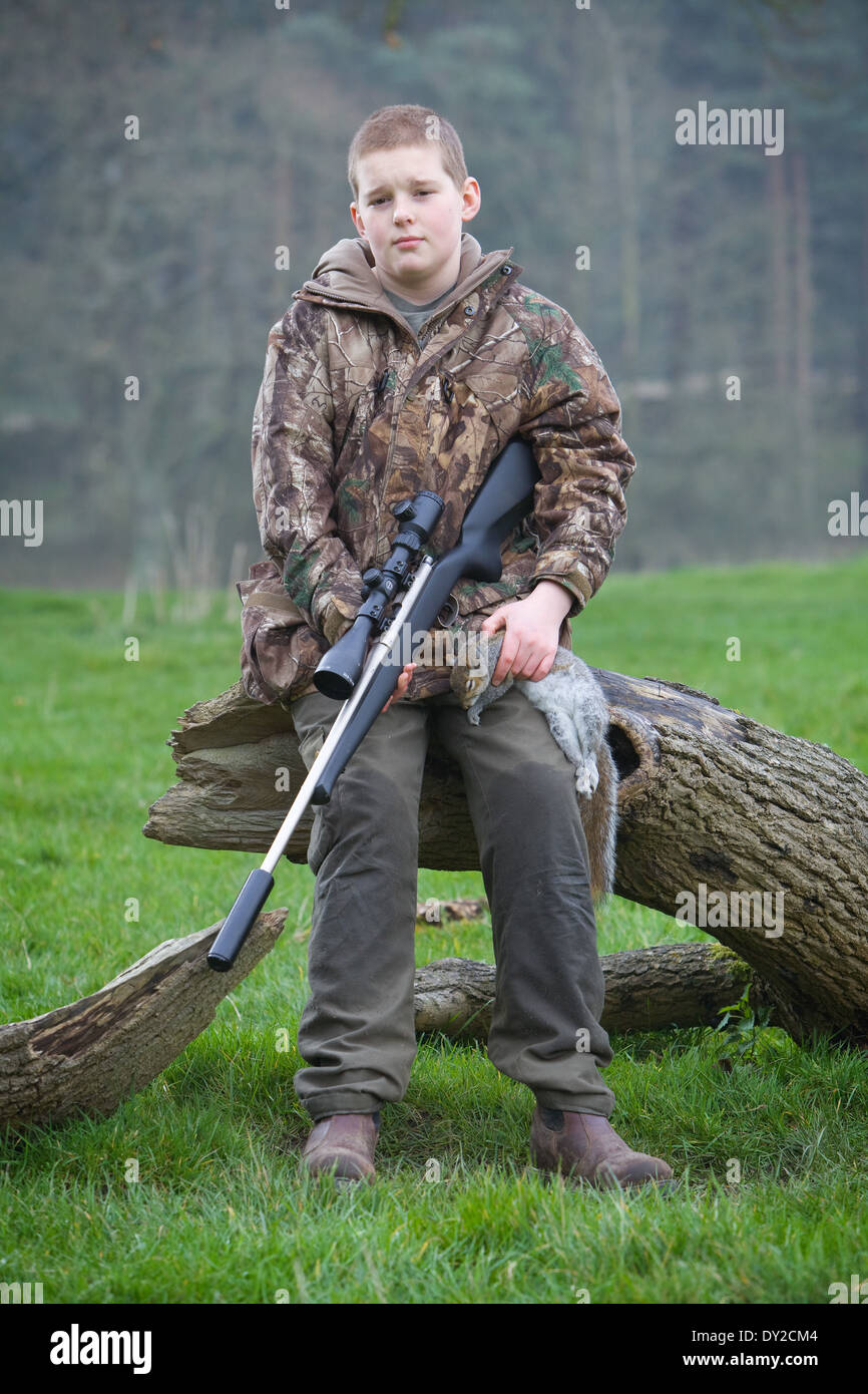 A young man with a rifle, shooting pests during the day in the countryside Stock Photo