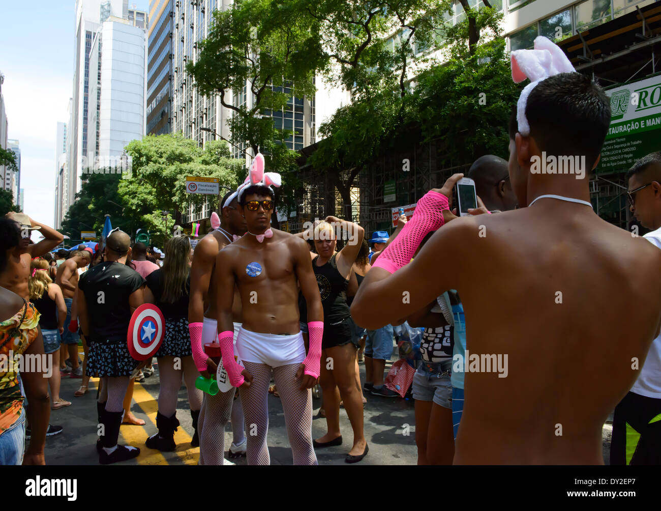Man dressed as pink playboy bunny photographing another on mobile phone, street party, Rio Carnival, Rio de Janeiro, Brazil Stock Photo