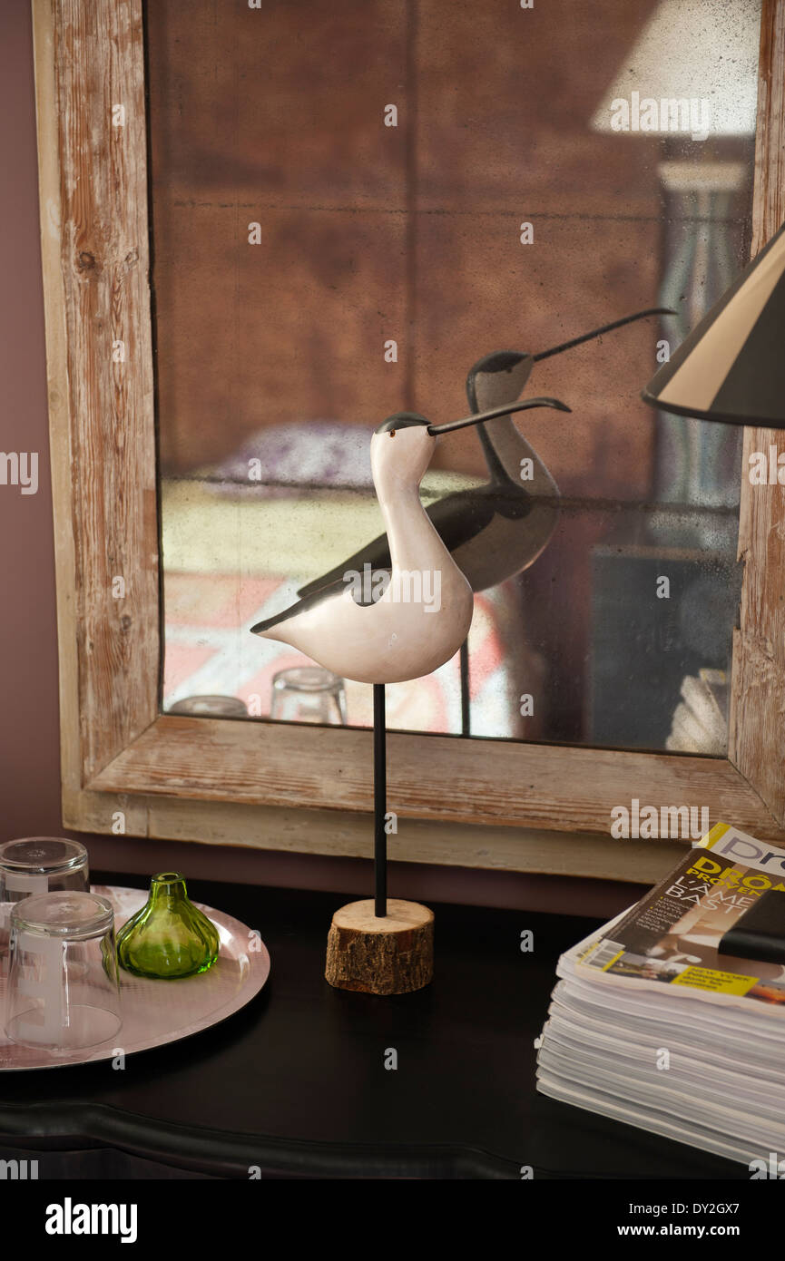 Detail of wooden bird decoration in front of a stripped wooden mirror Stock Photo