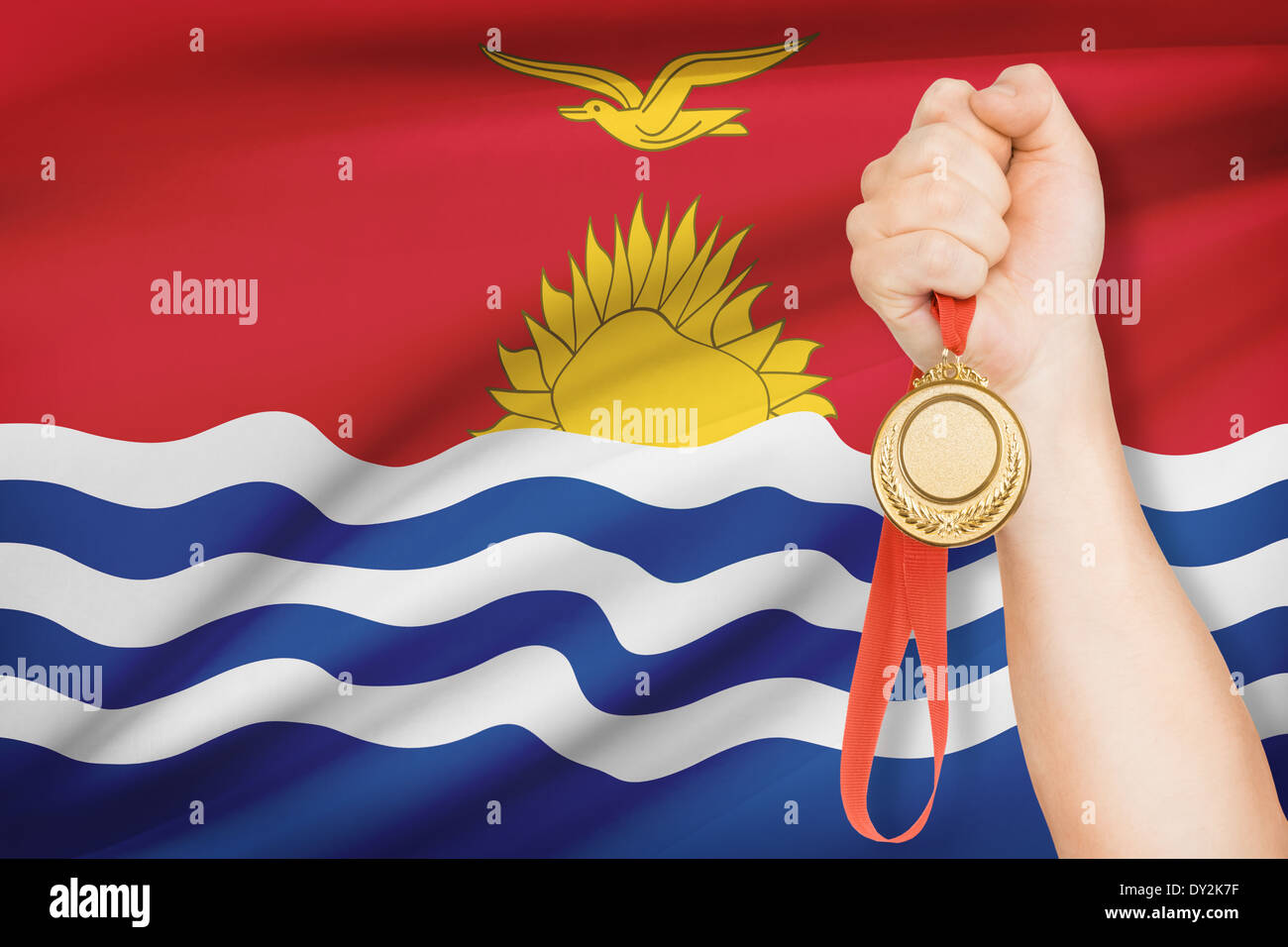 Sportsman holding gold medal with flag on background - Republic of Kiribati Stock Photo