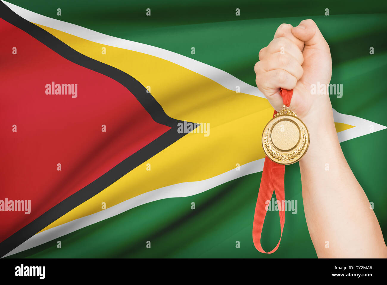 Sportsman holding gold medal with flag on background - Co-operative Republic of Guyana Stock Photo
