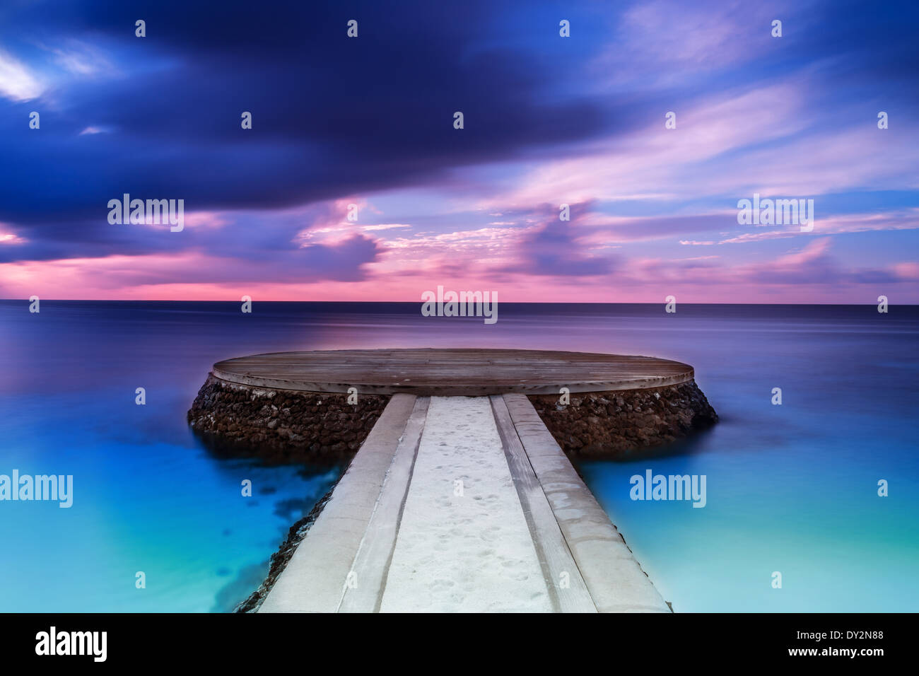 Beautiful pier in sunset, dramatic purple and blue cloudy sky, place for romantic dinner, luxury resort on Maldives Stock Photo