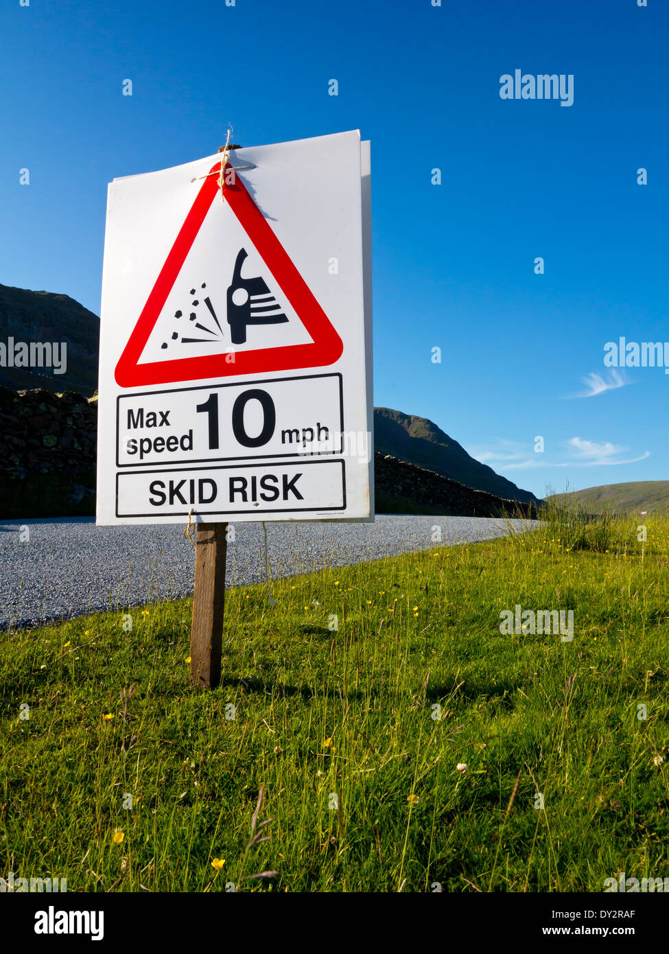 Newly resurfaced road with skid risk sign and 10mph speed limit to protect drivers against danger of loose chippings England UK Stock Photo