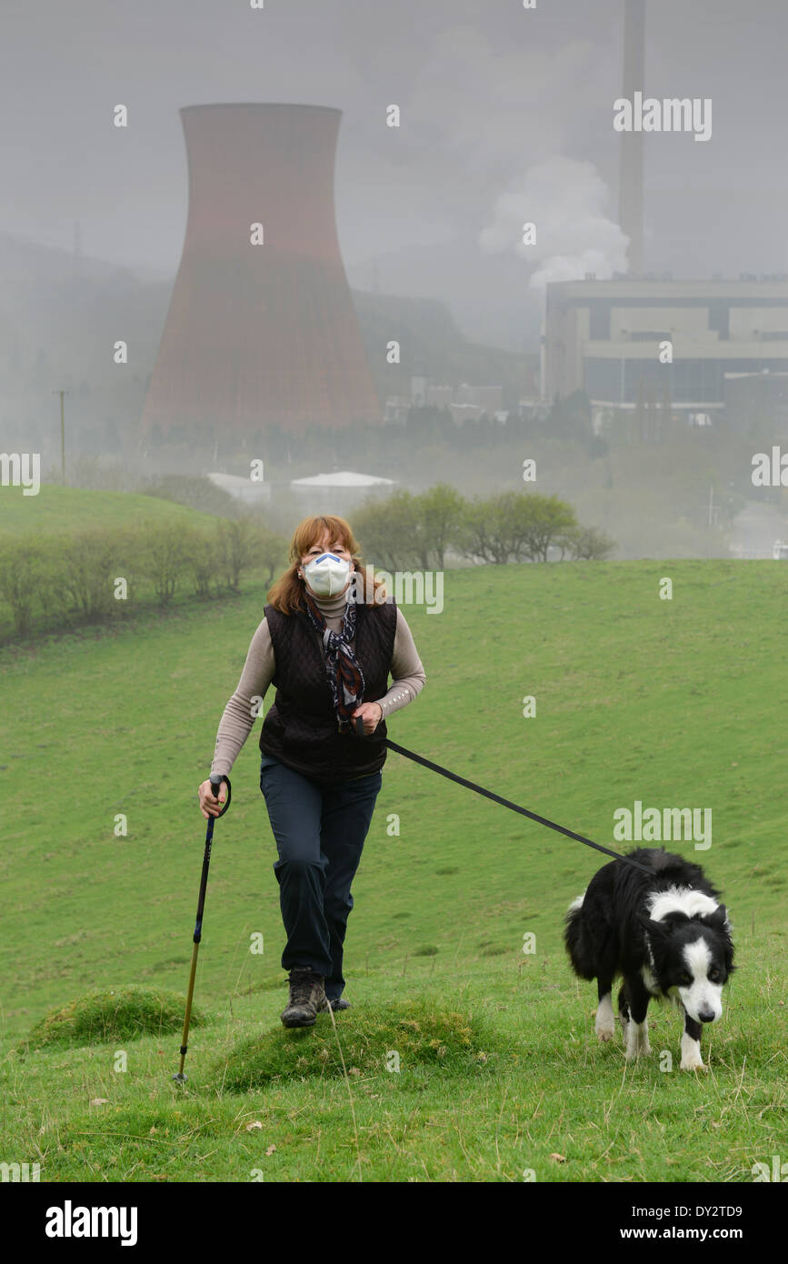 Woman wearing smog mask while walking dogs near Ironbridge Power Station due to smog pollution in UK Stock Photo