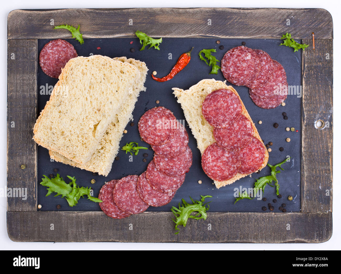 Cut bread with slices of spicy salami shot from above Stock Photo